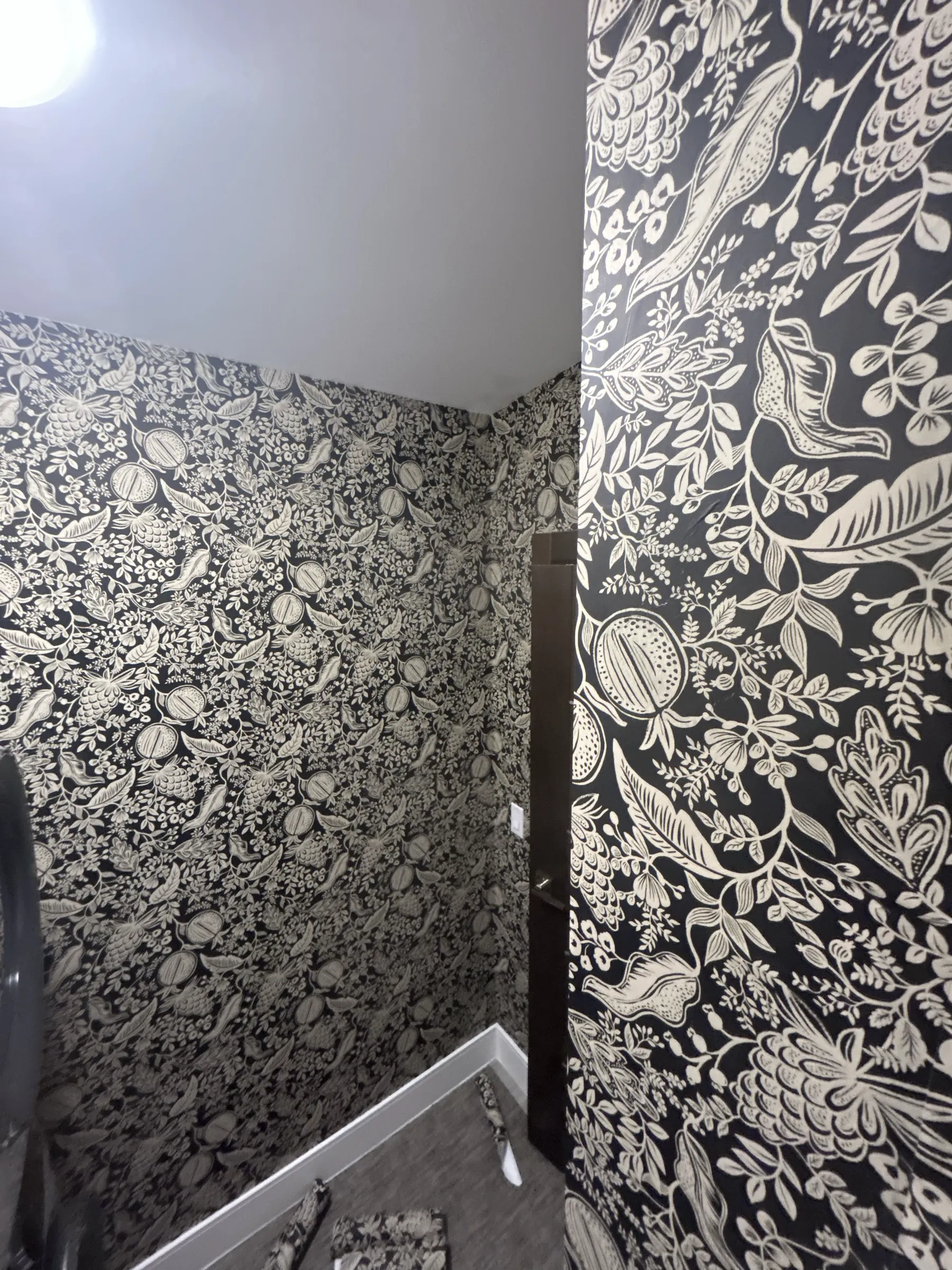 A small room wrapped in a black and white botanical, with a doorway