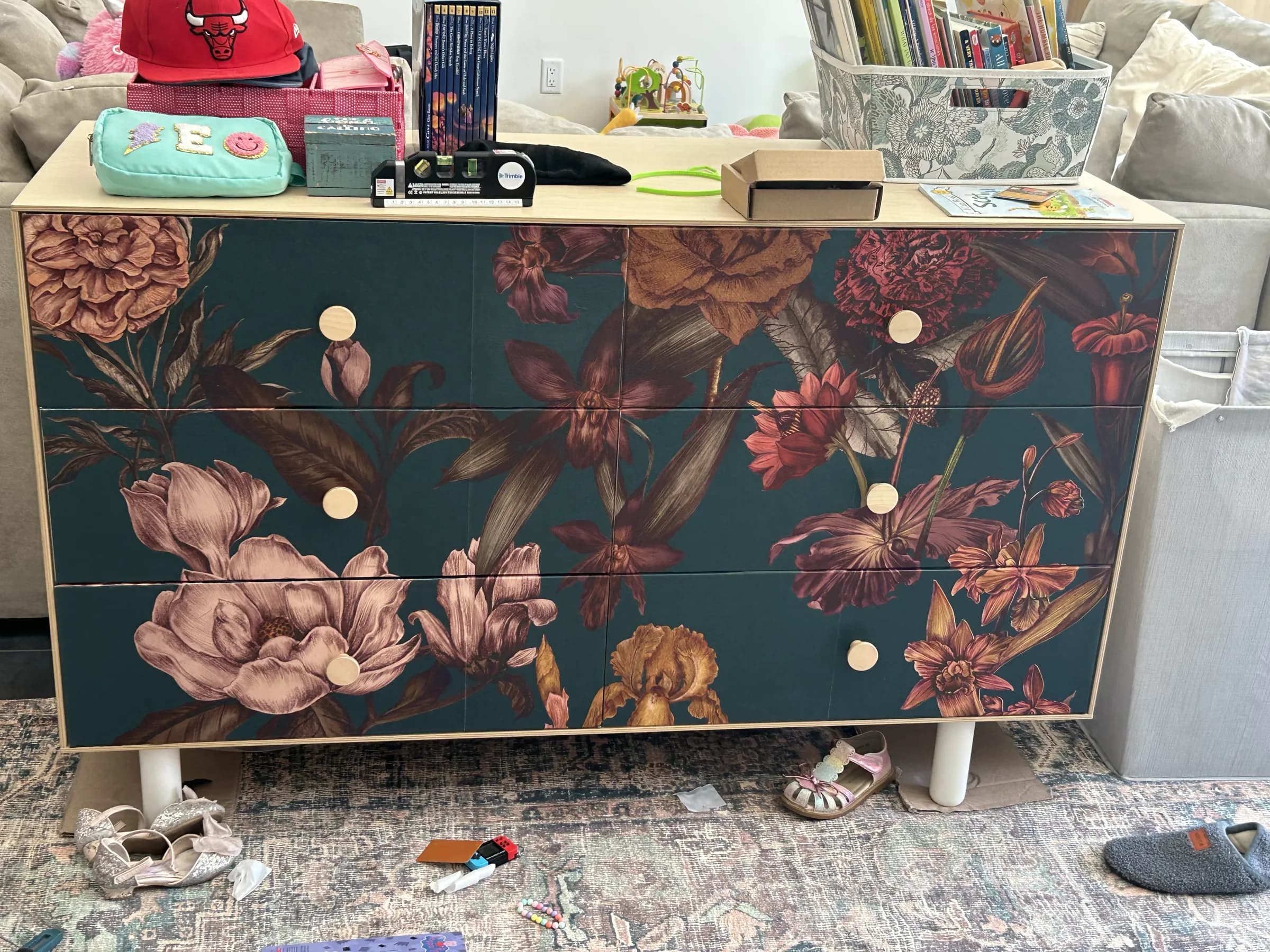 A dresser wrapped in dark floral wallpaper