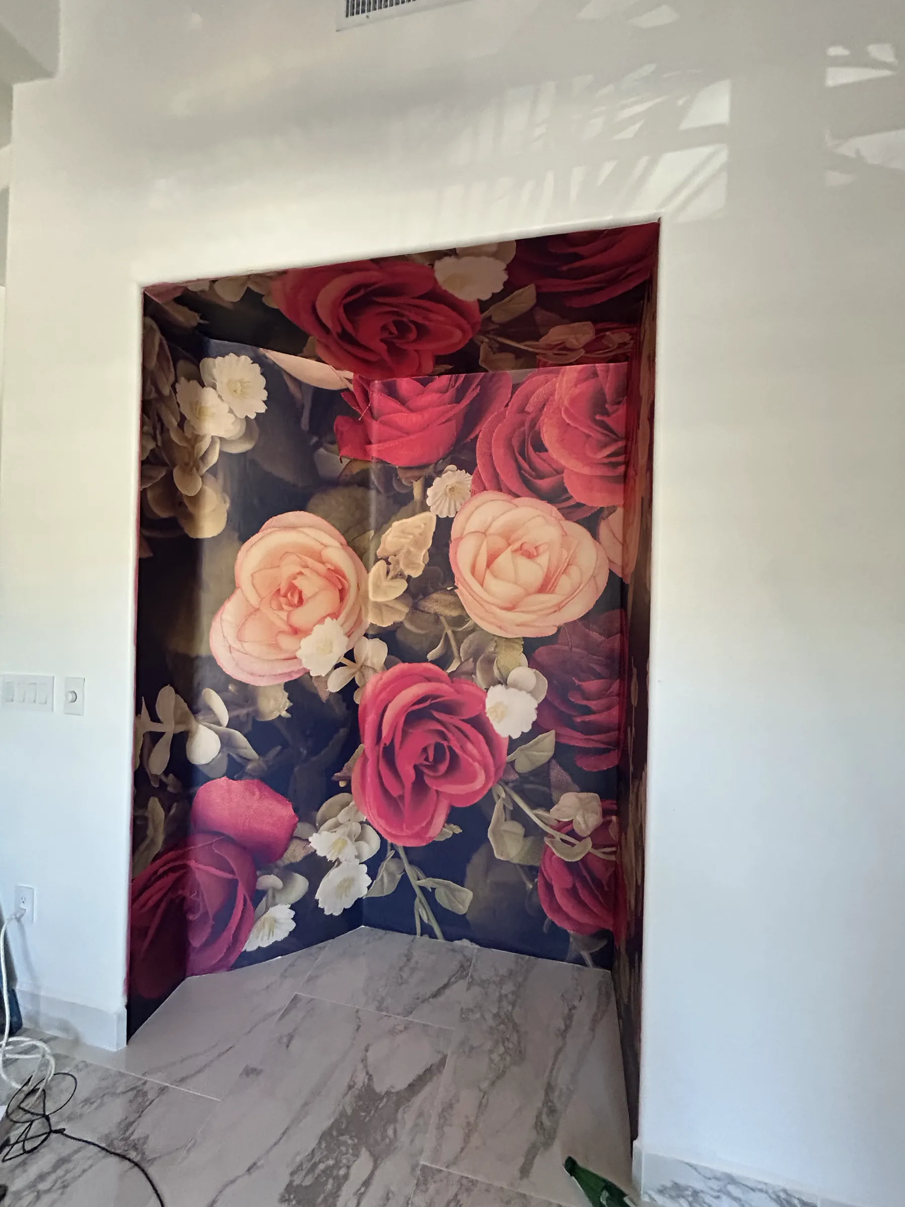 A tiled alcove lined floor to ceiling in a large red and pink rose mural