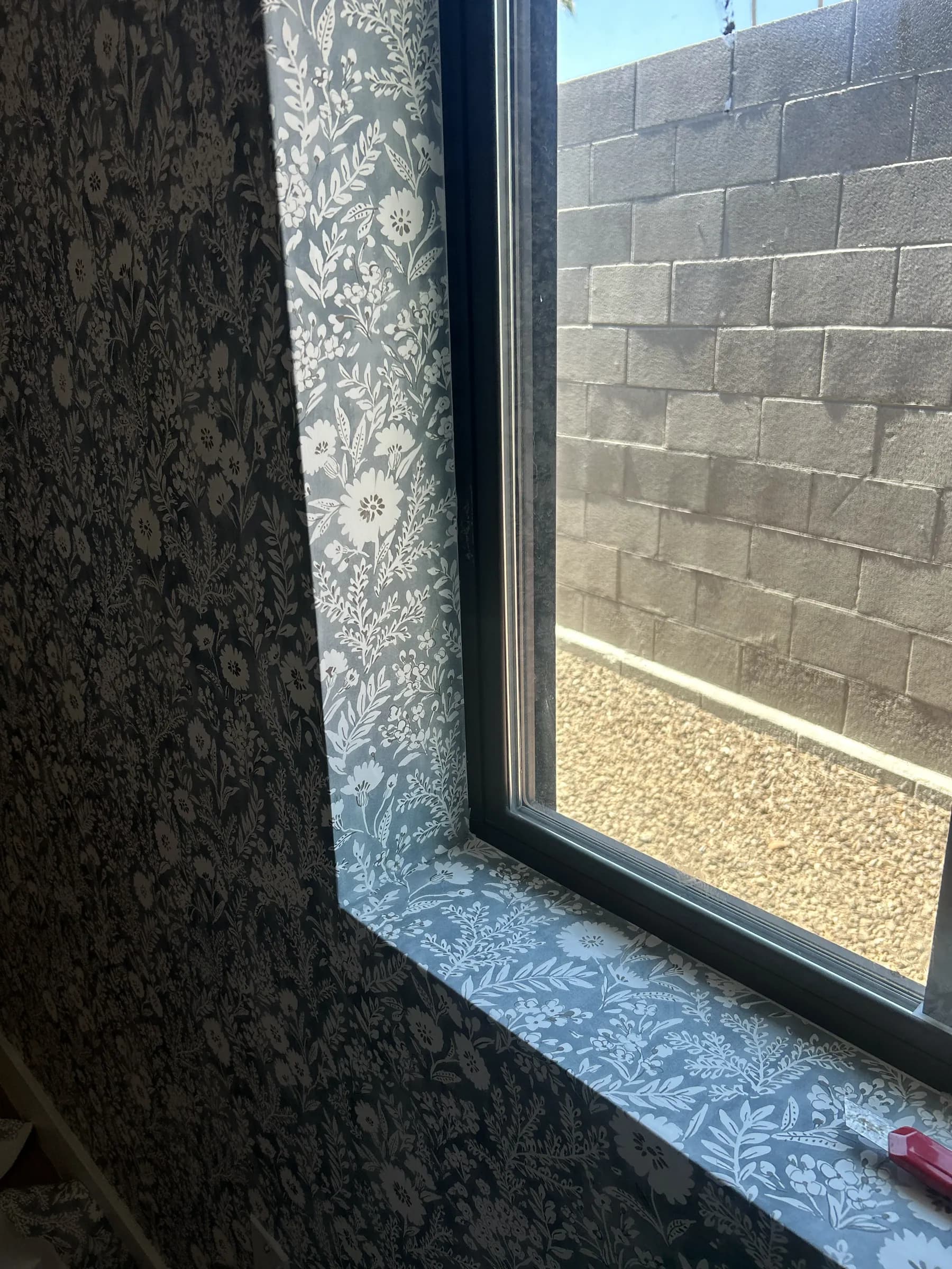 A deep window recess wrapped in slate botanical wallpaper