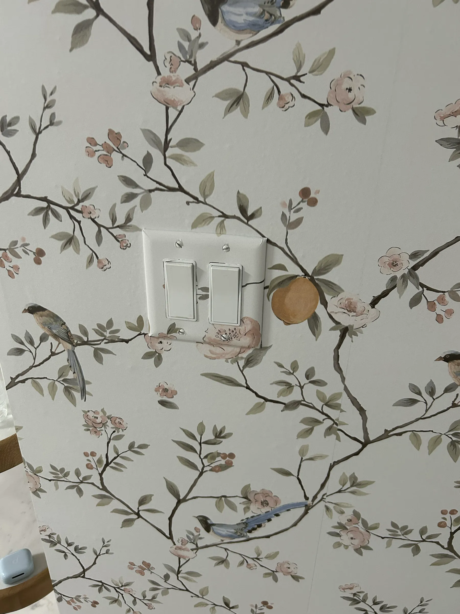 Close-up of a chinoiserie bird and blossom paper around a light switch