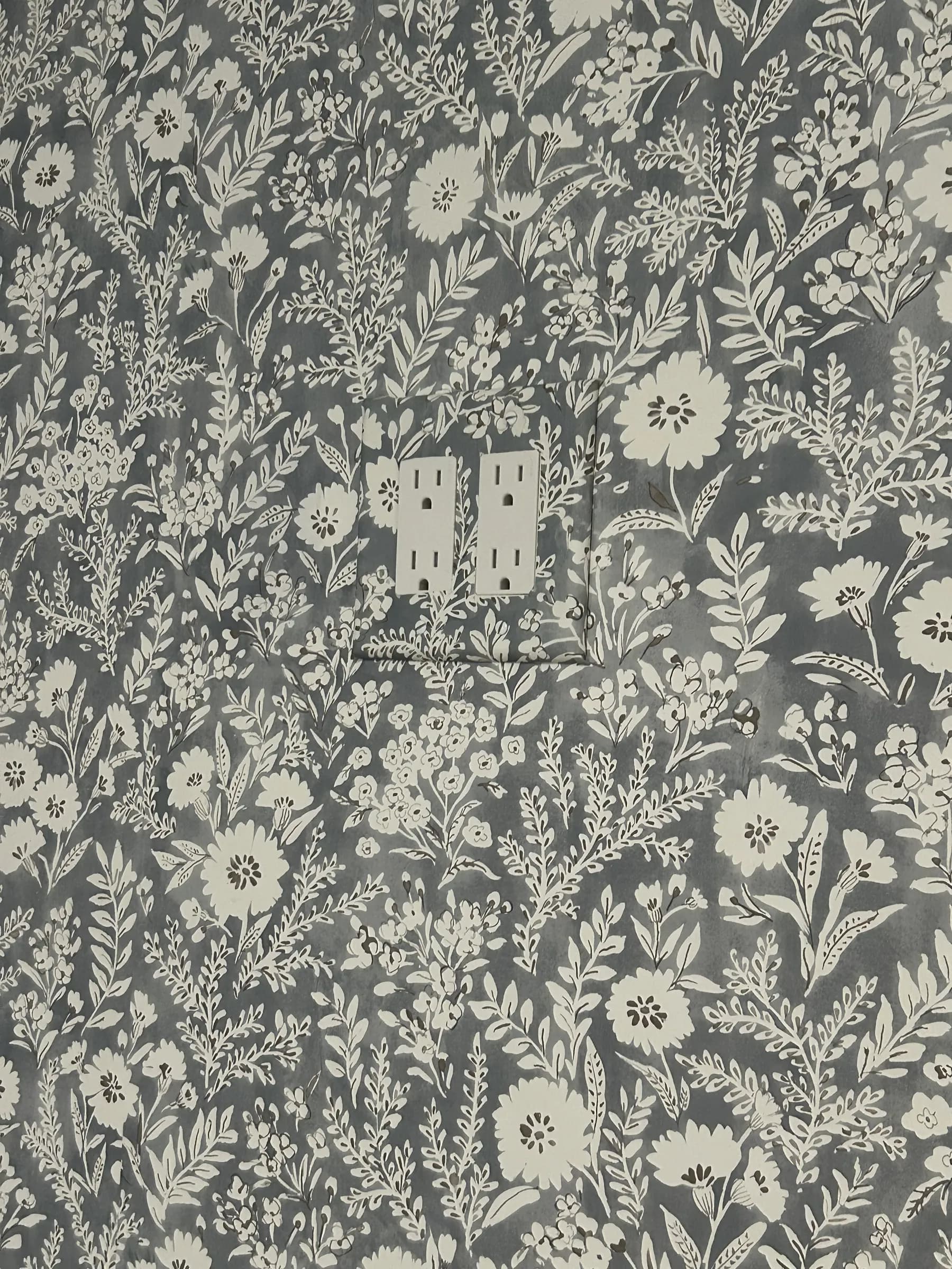 Close-up of slate botanical wallpaper cut neatly around an outlet