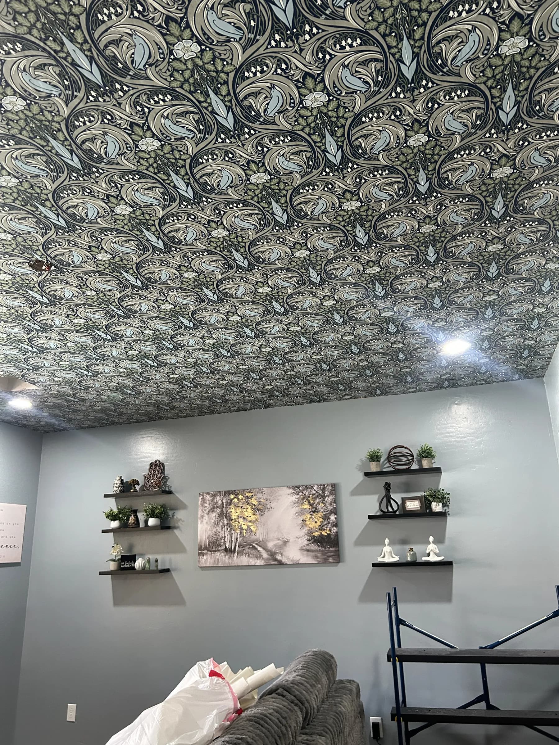 A ceiling papered in a dark green Nouveau botanical over a gray room