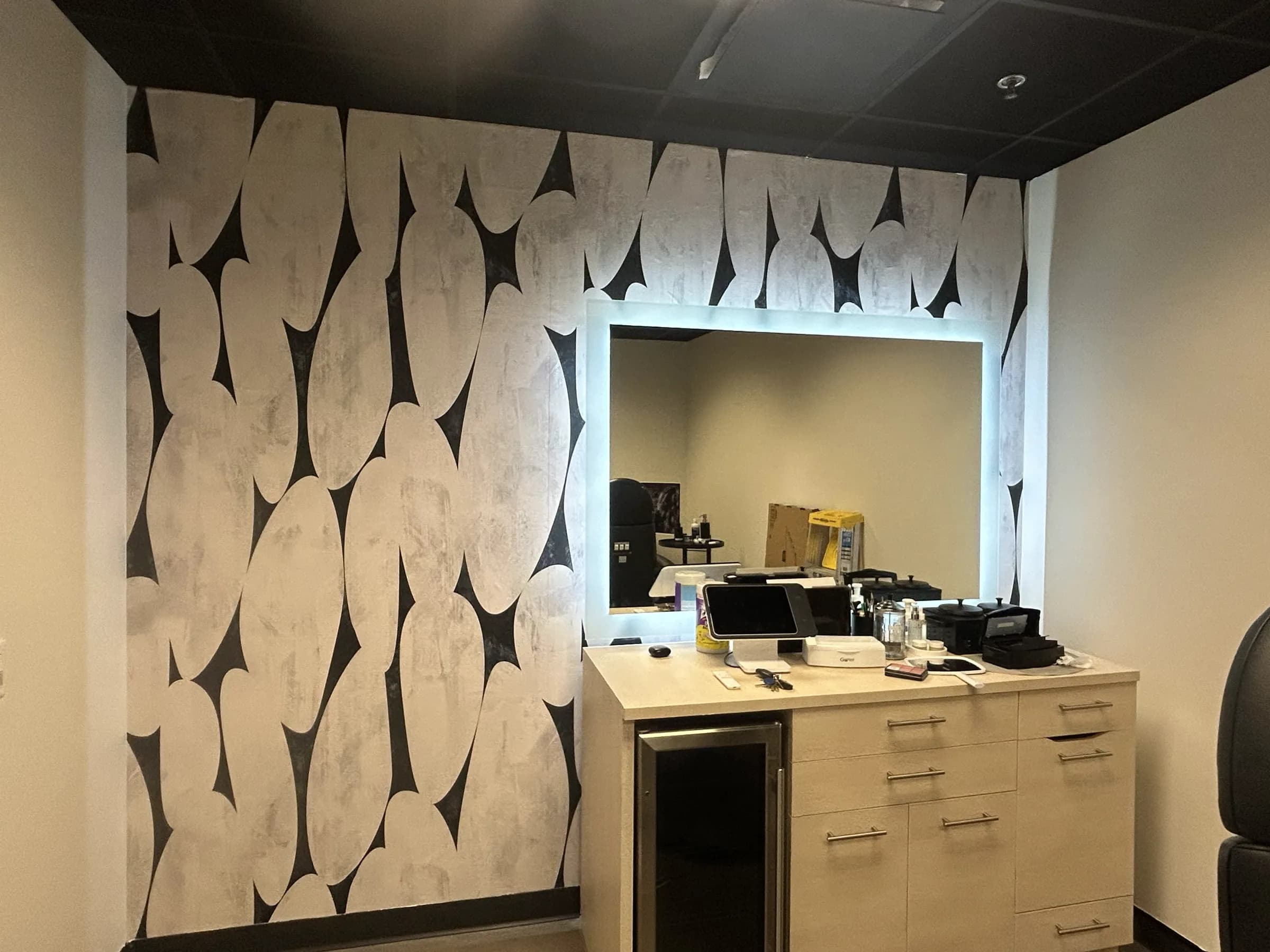 A salon suite with a black and white pebble-shape feature wall behind the mirror